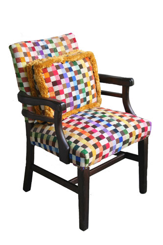 A standard armchair reinvented with needlepoint with an extra pillow